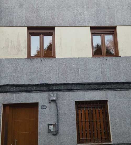 Fotografía de la fachada de una casa con ventanas rústicas en color nogal, eficientes. Proyecto hecho por Top Ventana reforma junto con su red de profesionales.